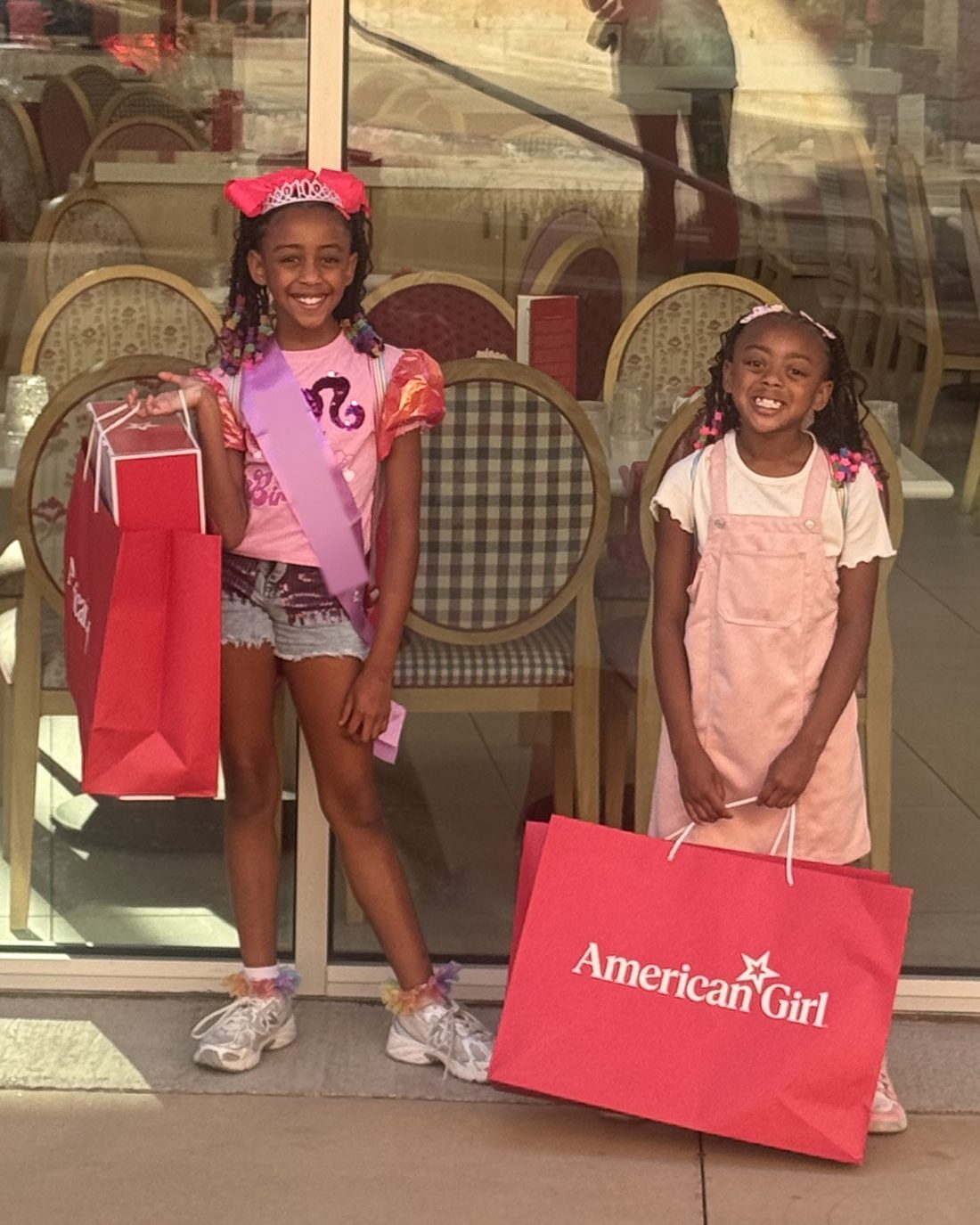 Mila G and Mati K smiling with shopping bags outside a café