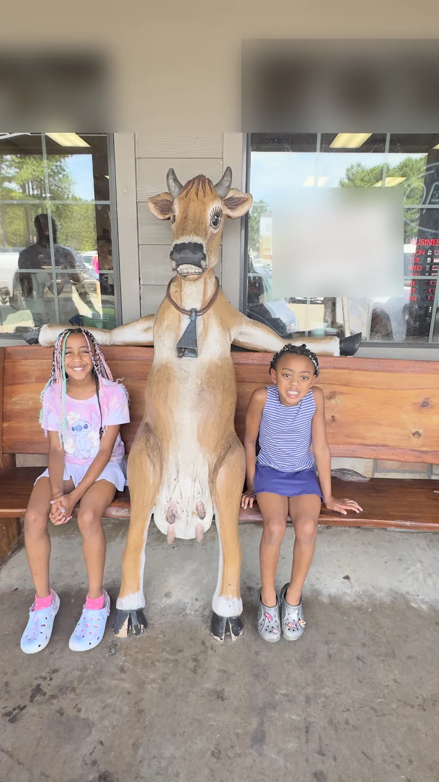The sisters sitting on a bench on either side of a cow statue